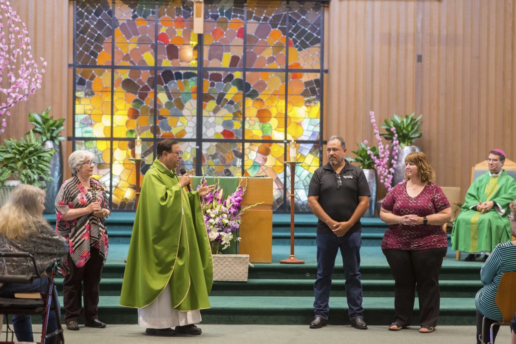 Father George Aranha witnessing one family give the Vocational Cross to another family at 
Sunday's Mass welcoming Bishop Oscar Cantú to Santa Teresa Parish
