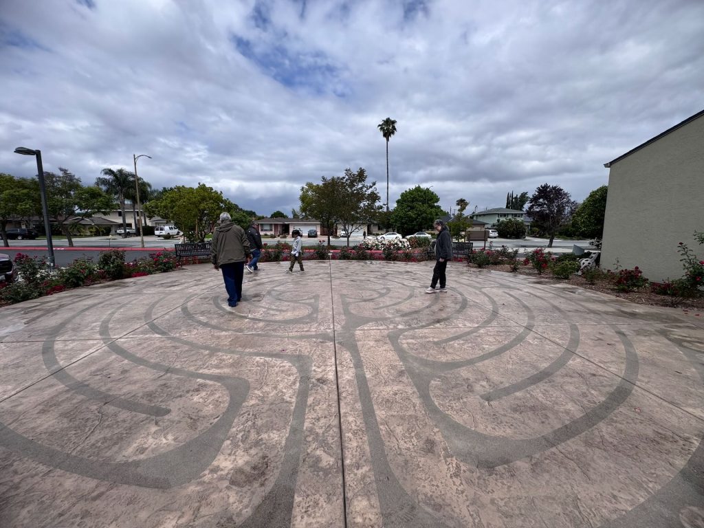 Wide view of the prayer labyrinth at Santa Teresa Church in San Jose with visitors walking the path